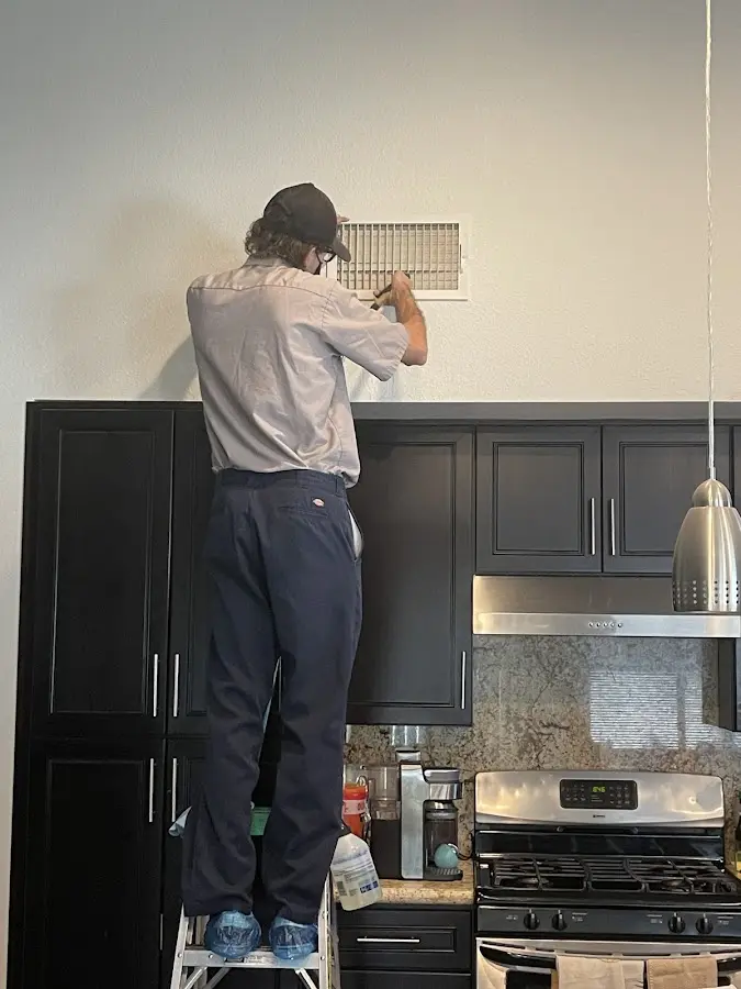 Technician inspecting an air vent during HVAC service in Dexter
